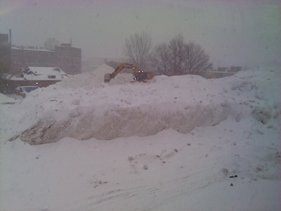 Earth moving equipment managing a multistory tall pile of snow
